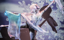 A ballerina performing on stage dressed in a winter themed costume