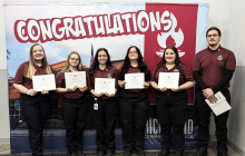 Photo of spring 2025 EMT graduates standing while holding their certifications