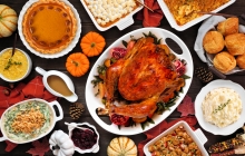 Table of thanksgiving food including a turkey at the center