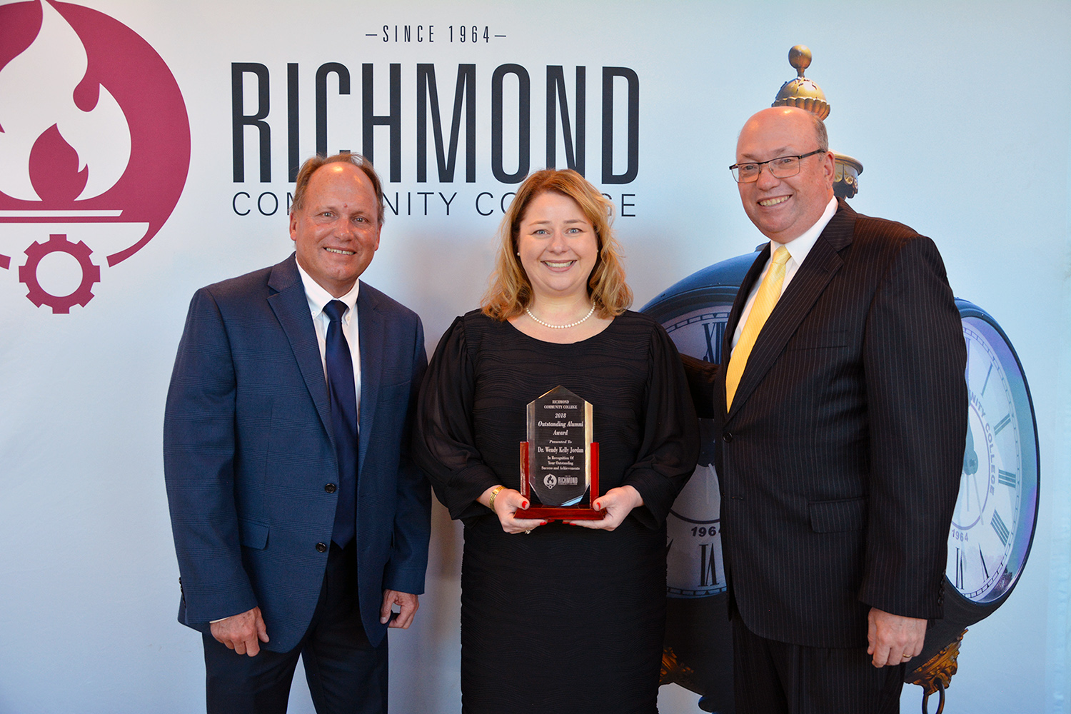 Dr. Wendy Jordan holds her award and stands with Dr. Hal Shuler and President McInnis.
